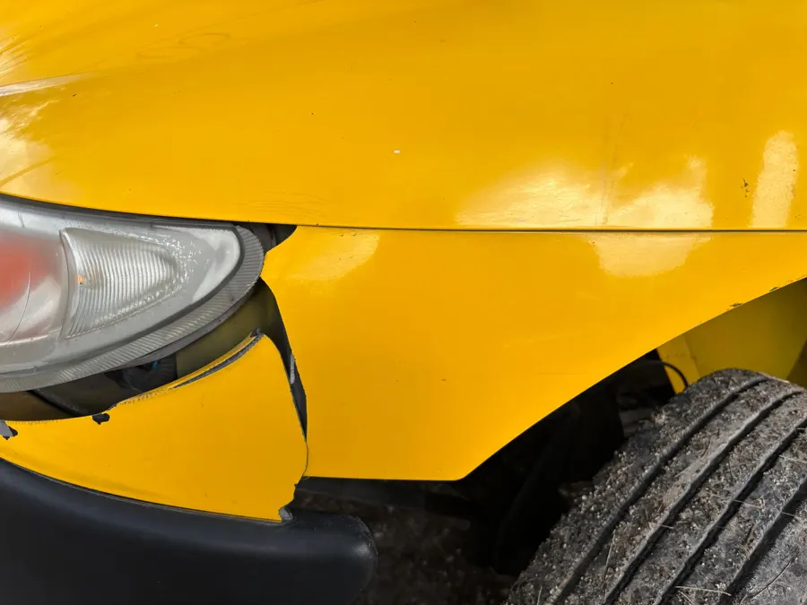 Beispielfoto: Eingedrückter Kotflügel an einem gelben Auto